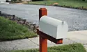 An image of a white mailbox with a red post.